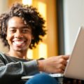 Persoană zâmbitoare care învață online, cu laptop